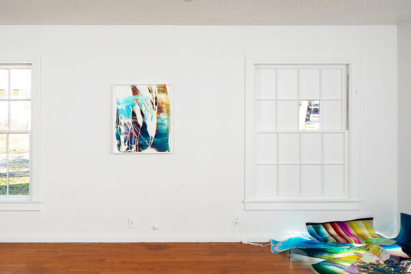 installation view of works on a wall, installed in a window, and on the floor