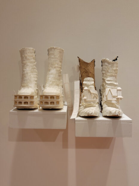 Boots made of cardboard with miniature models of homes carved into them