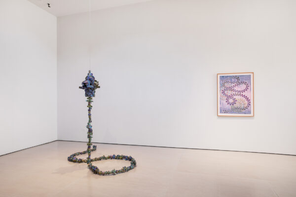 Installation view of a sculpture next to a two dimensional work hanging on a white wall