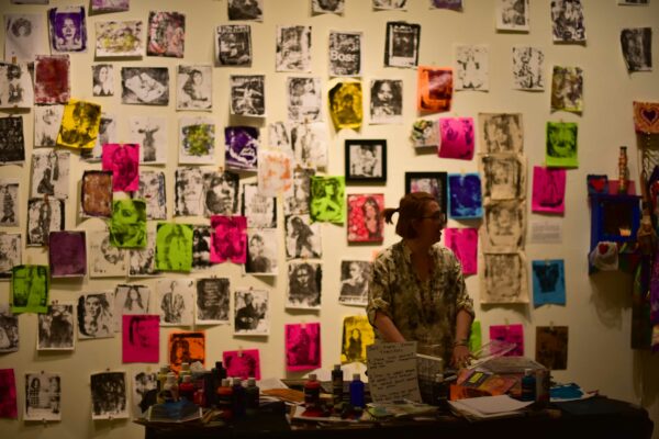 A woman standing in front of a wall of prints