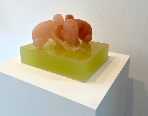 A small resin sculpture by Rona Pondick of two human creatures huddled over a third larger humanoid creature.