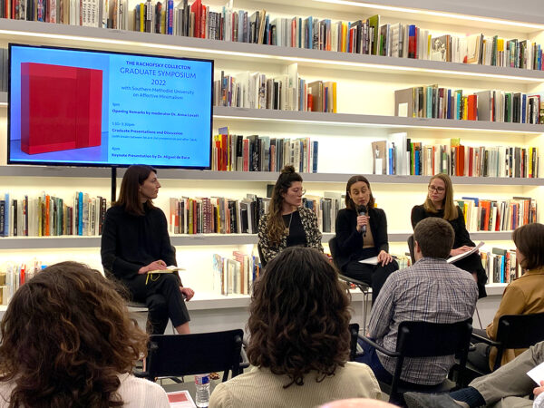 A photograph of a panel of scholars discussing their research in a library in front of a crowd.