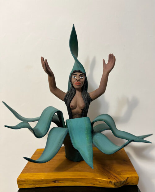 A clay sculpture by Veronica Castillo of a nude female figure emerging from a desert plant. 