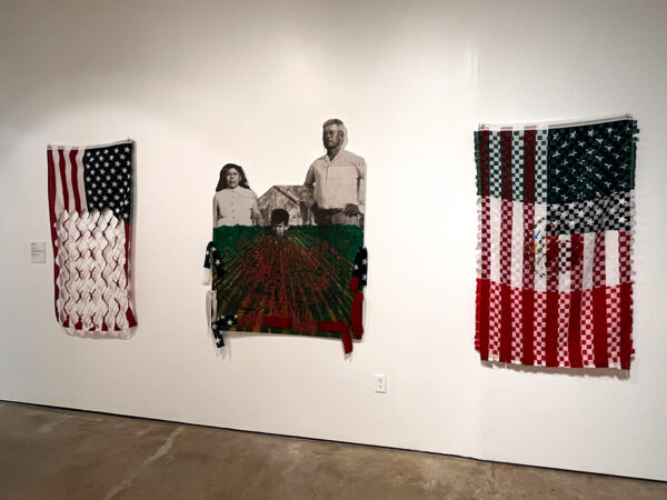 Sobre una pared blanca cuelga el tapiz de un retrato familiar al centro y dos banderas estadounidenses intervenidas a sus costados.