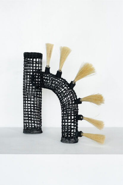 Black basket sculpture with reed tassels
