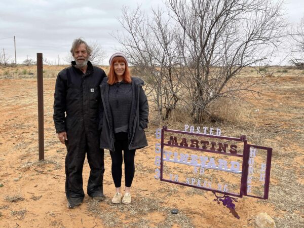 Photo of Kelly and Preston Alison next to a vineyard sign