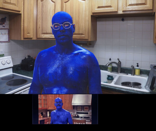 Two men painted themselves blue and standing in a kitchen