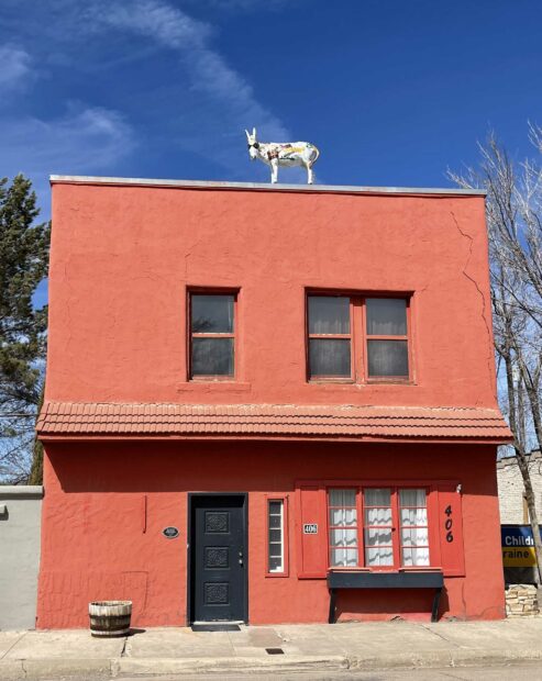 Red building with a sculpture of a white donkey wearing sunglasses on the roof