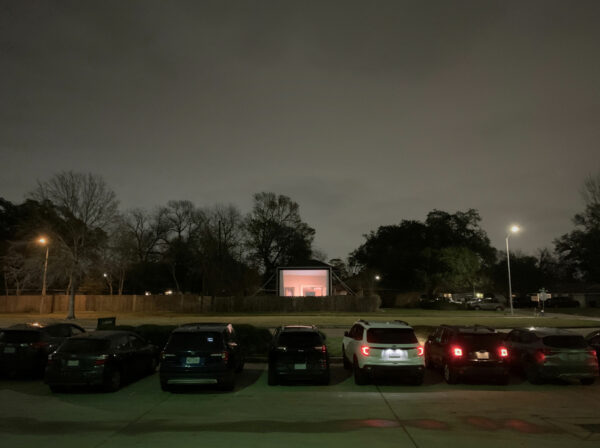 Cars in a parking lot watching movies on a large screen