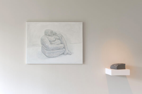 a small stone on a floating shelf on the right and a painting of a seated woman in canvas on the left