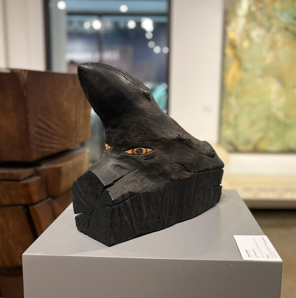A small wood sculpture by James Surls of a house-shaped piece of burned wood.