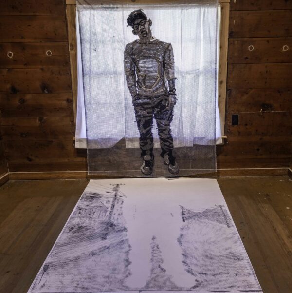Textile work of a figure standing above a drawing of the negative space of a figure
