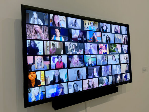 A still image of a screen displaying a grid of 42 videos of young women, each person is singing the same song. Artwork by Molly Soda.