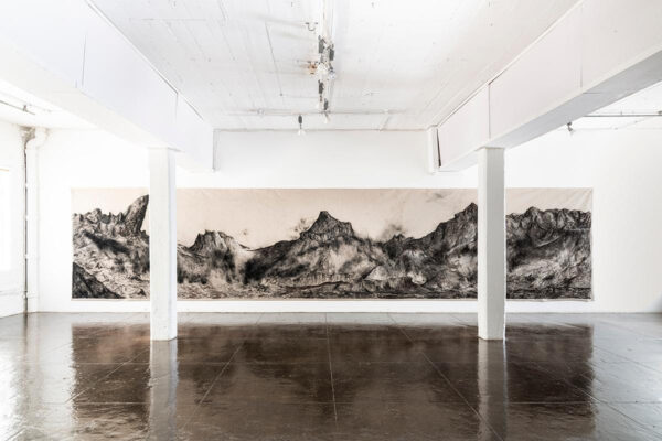 An installation photograph of a large-scale charcoal landscape by Nohemí Pérez.