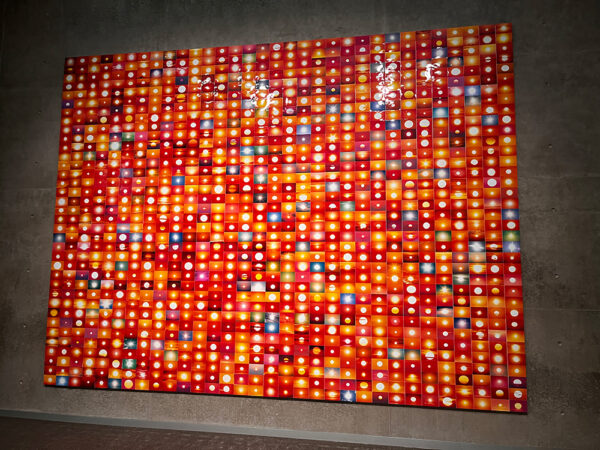 An installation photo of a large work by Penelope Umbrico featuring a grid of over 1,000 four-by-six-inch photographs of the sun.