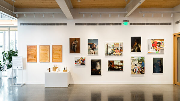 An installation image of a group show featuring paintings, photographs, sculptures, and prints.