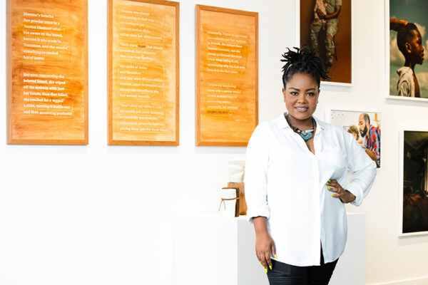 A photograph of artist Shavon Morris in front of works of art.