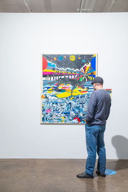 Installation of a colorful two dimensional painting with a visitor standing in front
