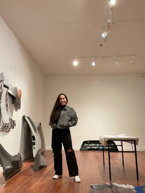 A photograph of artist Verónica Gaona standing in her studio with large-scale sculptural works behind her.