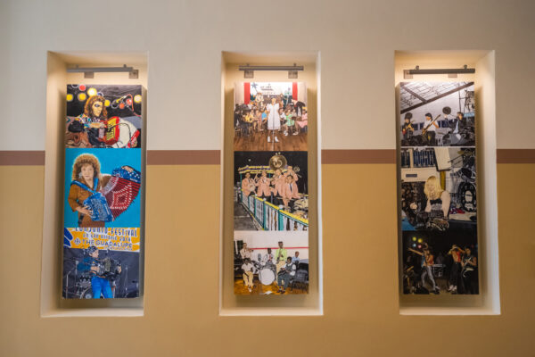 A photograph of three vertical paintings by Raul Rene Gonzalez featuring musicians, installed at San Antonio's City Hall.