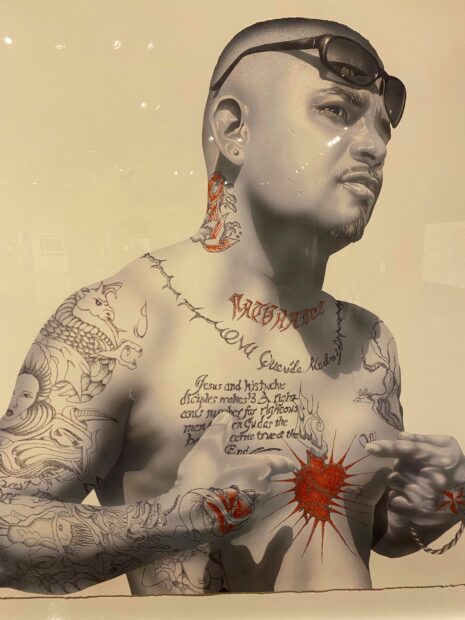 Portrait of a Chicano man shirtless displaying tattoos