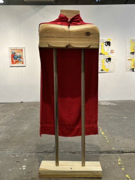 A red towel hanging on a stylized wood figure