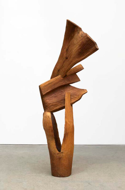 A photograph of a wooden sculpture made from three pieces of walnut that have been shaped and stacked on top of each other. Artwork by Thaddeus Mosley.