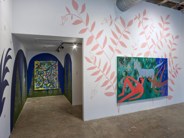 Installation view of pastel floral patterns on a wall and colorful landscape patterns