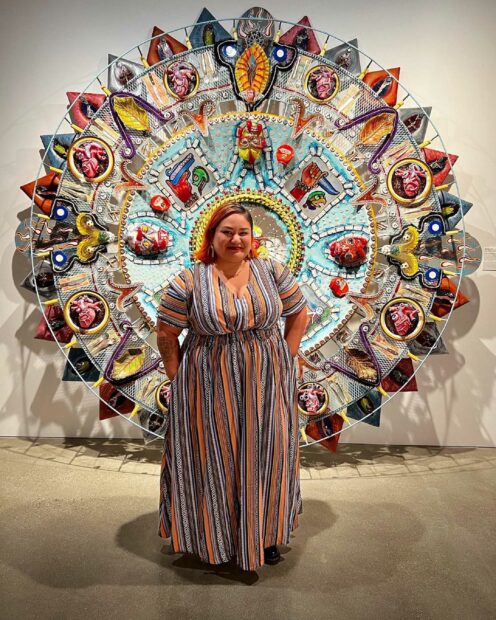 Photo with a woman standing in front of a large sculpture