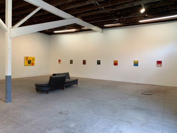 Artworks are installed in a white walled, concrete floor gallery space. 