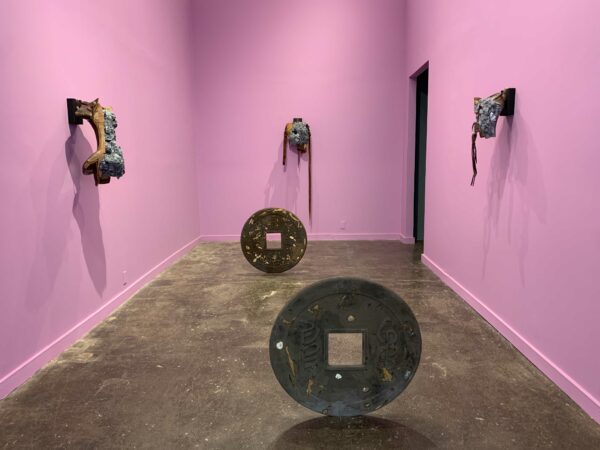 Gray-colored sculptures populate a small pink painted room.