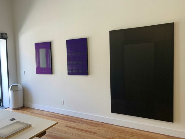 Three black and blue rectangular artworks hang on a wall.