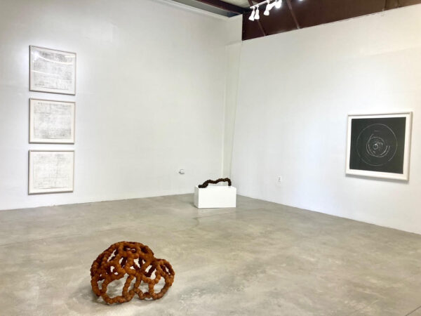 Installation view of works on a wall and sculptures on a floor