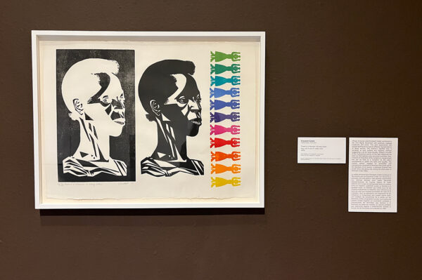 A photograph of a print by Elizabeth Catlett with English and Spanish text on the label next to it.