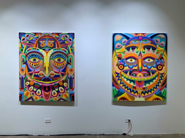 Brightly colored paintings of faces hang on a wall.