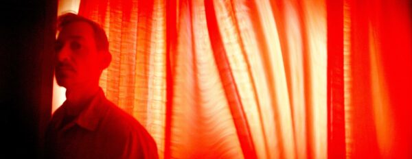 Photo of a person in front of an orange curtain