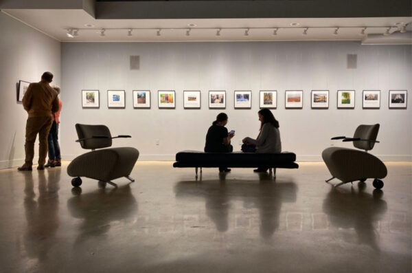 A photograph of people looking at artworks in a gallery.