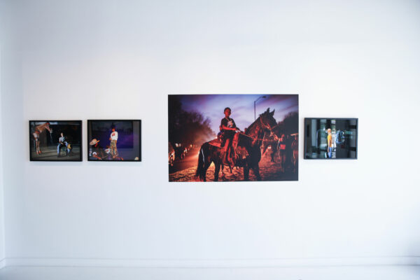 Installation view of photos of cowboys and children on a wall
