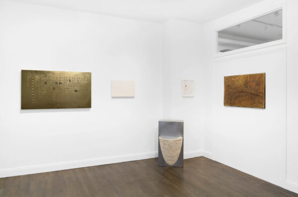 Installation image of gold works on a wall and a sculpture in a corner