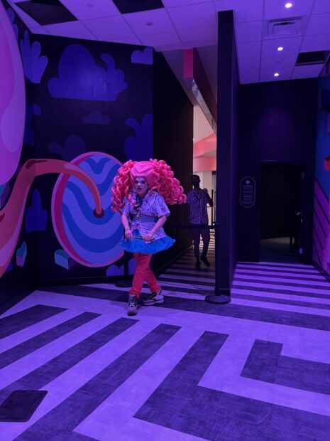 A photograph of a greeter at the entrance of Meow Wolf "The Real Unreal."