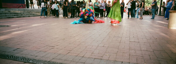 A photograph of performance artist Christian Cruz standing next to a piñata.