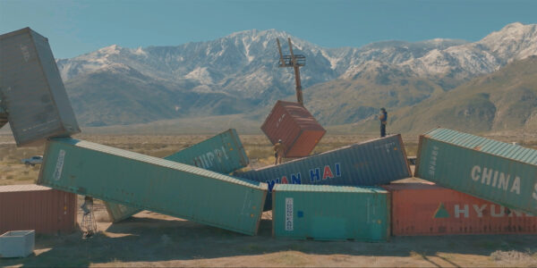 A still image from a video of large shipping containers being stacked in place.