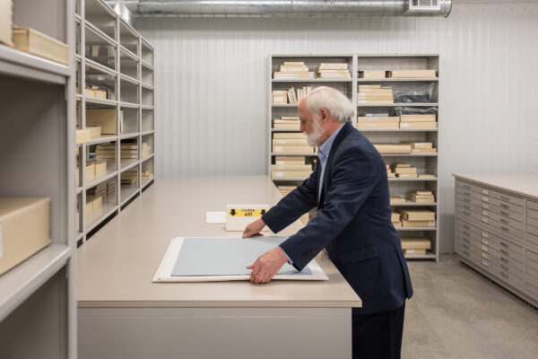 A photograph of curator John Rohrbach handling artworks in storage at the Amon Carter Museum of American Art.