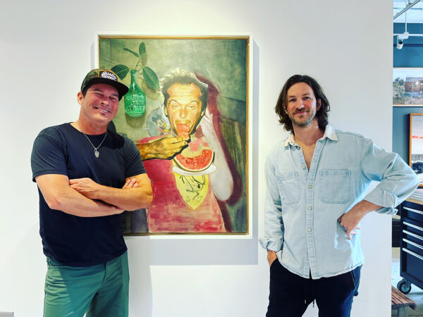A photograph of gallerist Bale Creek Allen and artist Jay Wilkinson standing in front of a painting by Jay at Bale Creek Allen Gallery.
