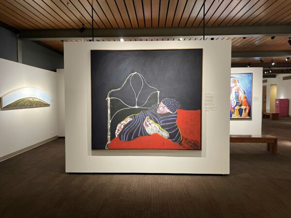 Installation view of a painting with a black background with a dying warrior at the foreground