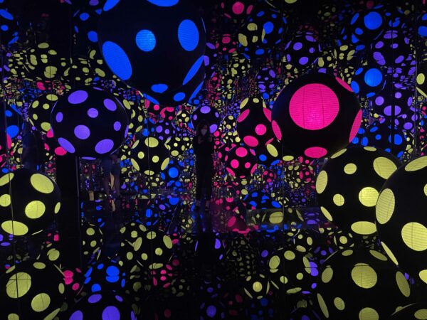 The author in an infinity room with blue, pink and yellow balls