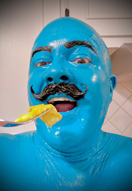 A photograph of a man covered in blue paint.