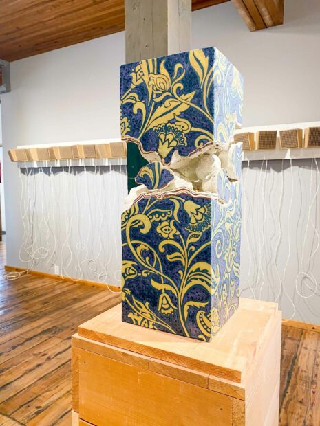 Installation image of speakers on a wall and a floral patterned column