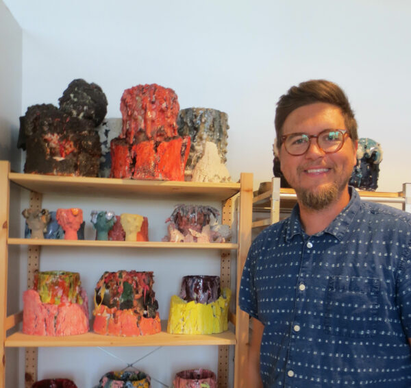 Portrait of Adam Knoche in his studio with ceramic pieces in the background