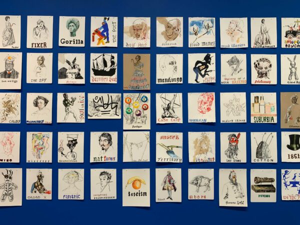 Many unframed small-scale artworks, which each feature a drawing that is captioned by a few words, hang in a perfect grid on a blue wall.